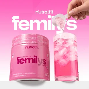 Pote rosa do probiótico Femilys da Nutralfit ao lado de um copo com bebida rosa e gelo, com a mão de alguém despejando o pó com um dosador