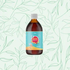Frasco de vidro escuro com tampa branca do Suplemento Kids Nature's Prime, com rótulo colorido e ilustração infantil, sobre fundo verde claro com folhas